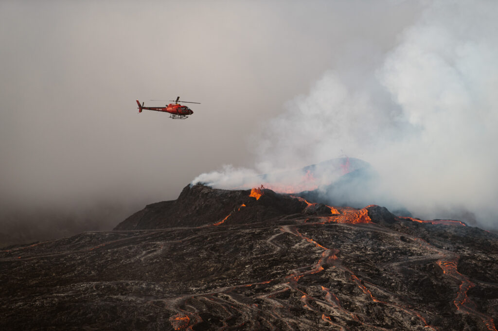 View of helicopter flying over erupting volcano in Iceland