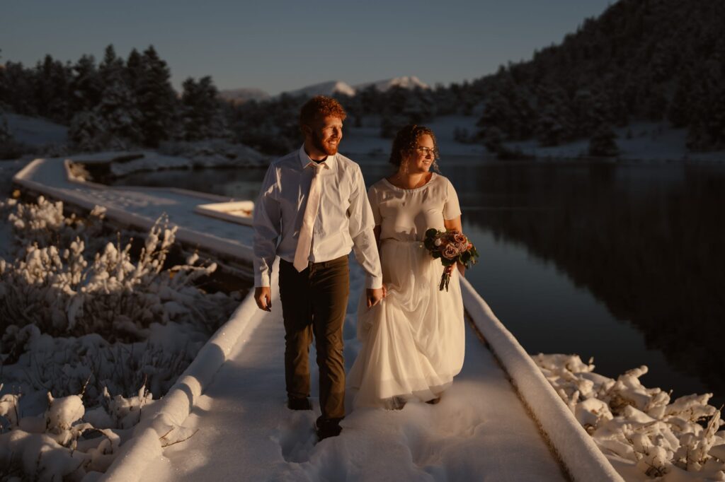Couple glowing in the sun walking around a snowy lake in Colorado