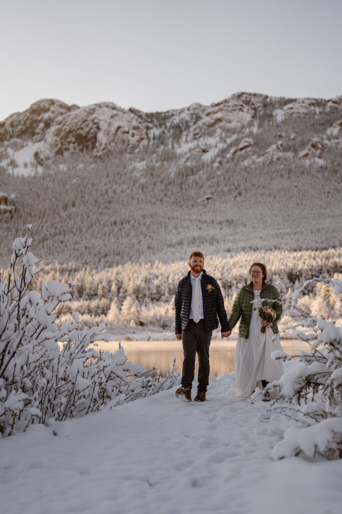 Bride and groom walking at snowy Lily Lake in Rocky Mountain National Park