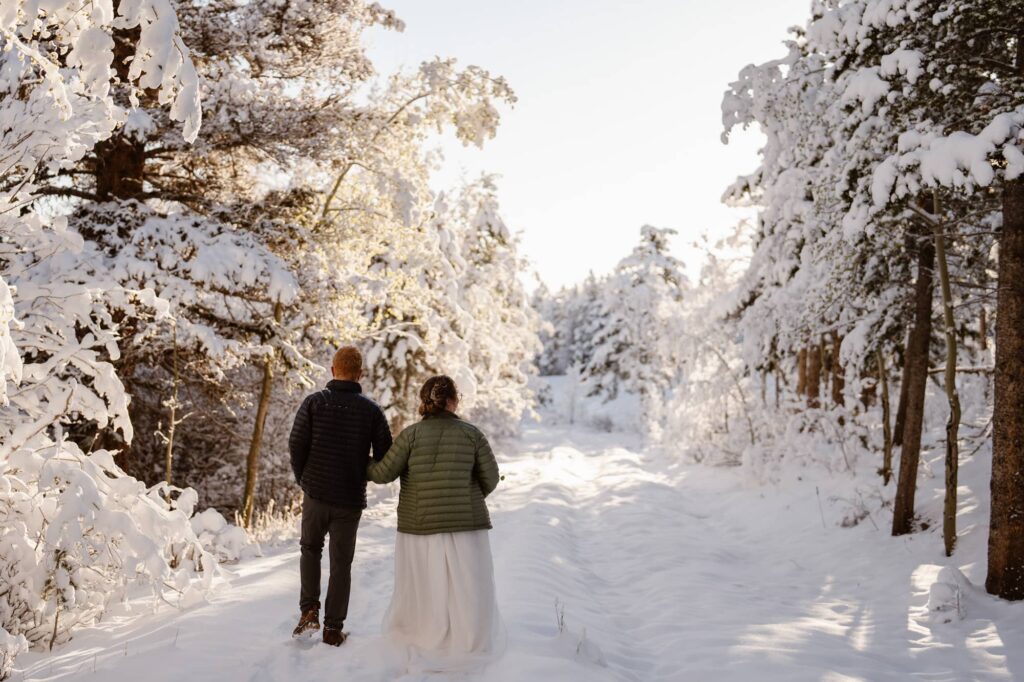 Wedding couple walking through a winter wonderland at Lily Lake in Colorado