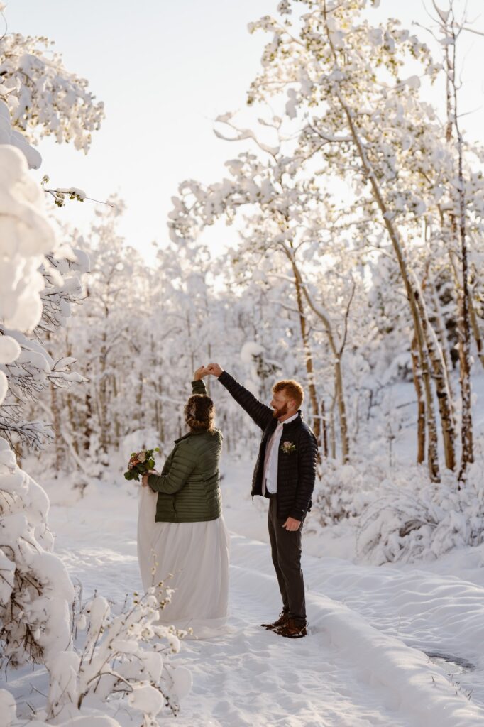 Bride and groom dancing in a snowy winter scene with sunshine