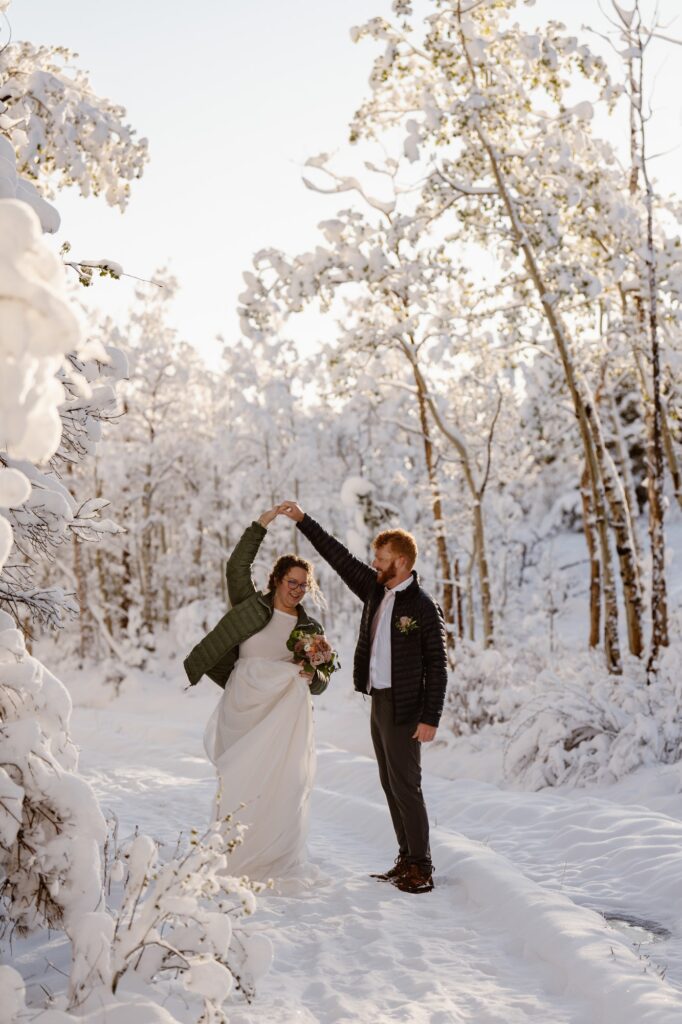Bride and groom dancing on a snowy trail at Lily Lake in Colorado