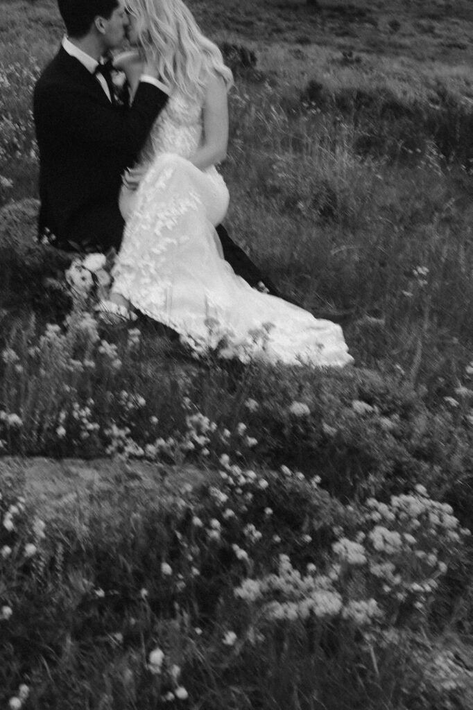 Bride and groom kissing amongst wildflowers