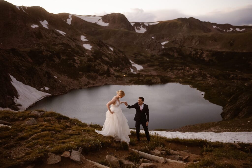 Bride and groom hiking above an alpine lake in Colorado during their elopement