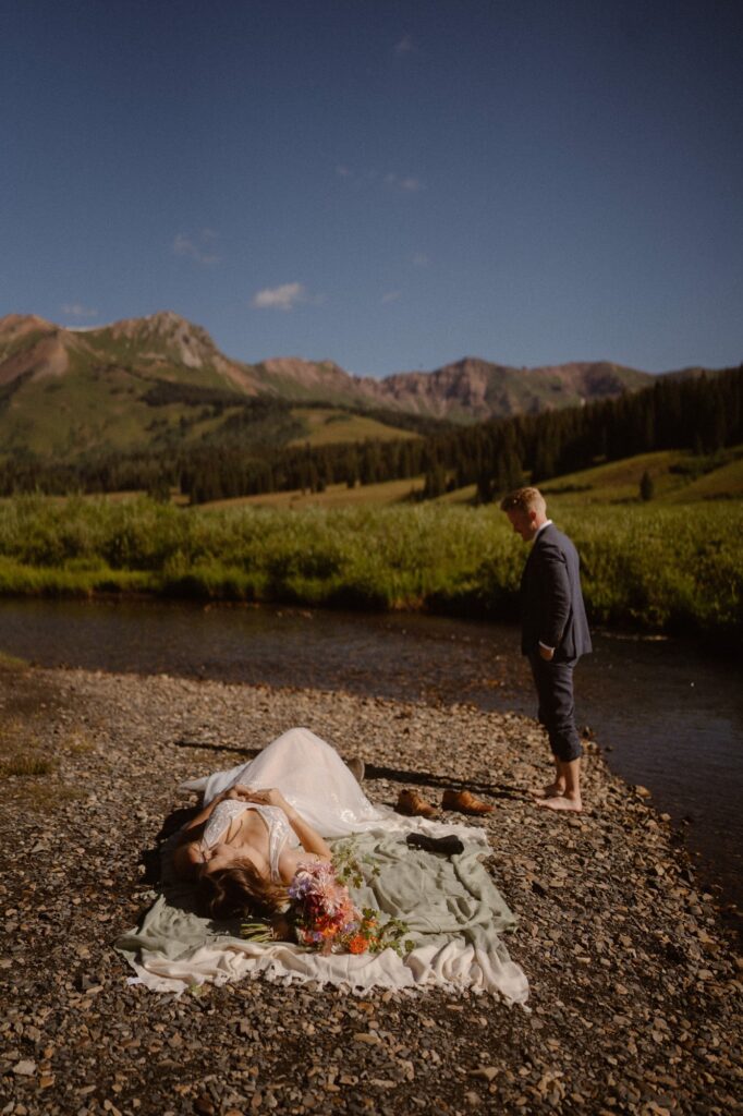 Bride and groom laying by the river on their elopement day