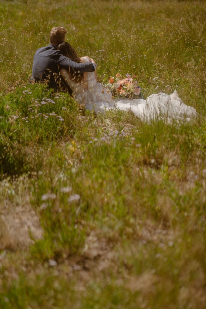 Couple snuggled in a field in their wedding attire