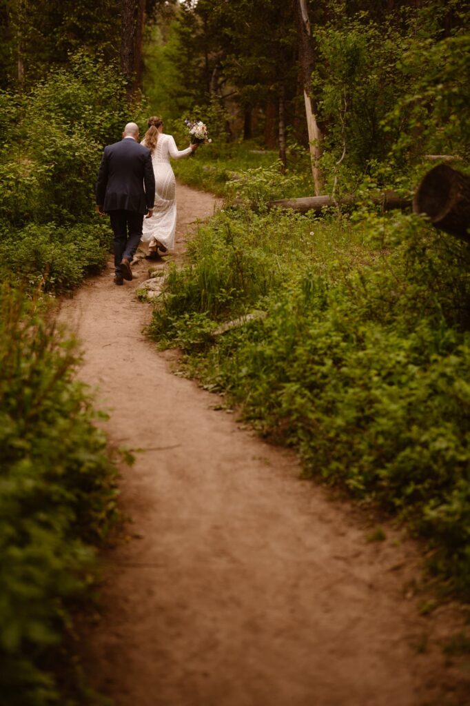 Couple hiking a winding trail on their elopement day in a Colorado forest