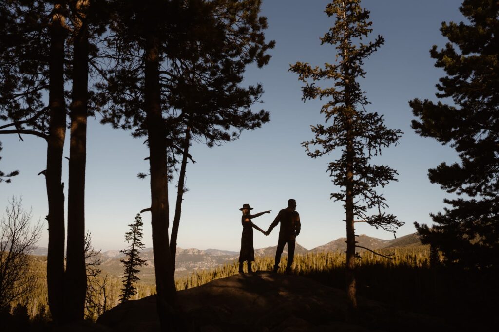 Silhouette of couple pointing off into the distance in the mountains