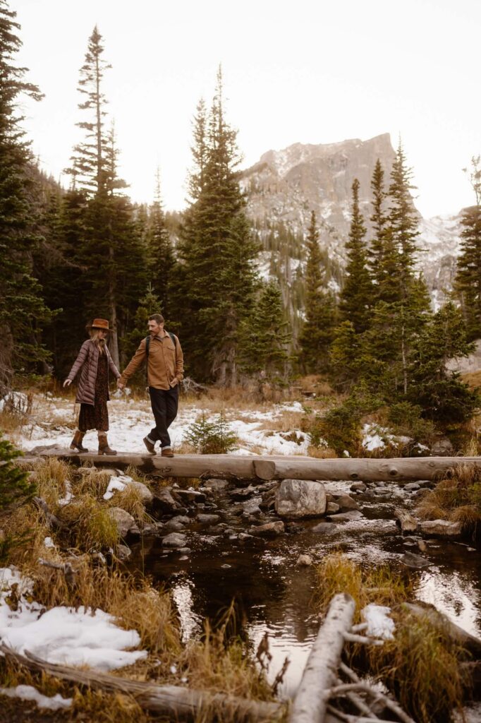 Couple crossing a log bridge during their engagement session