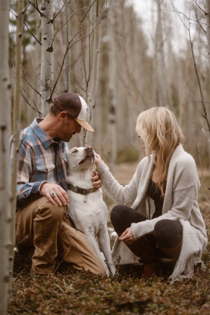 Couple loving on their dog in the forest