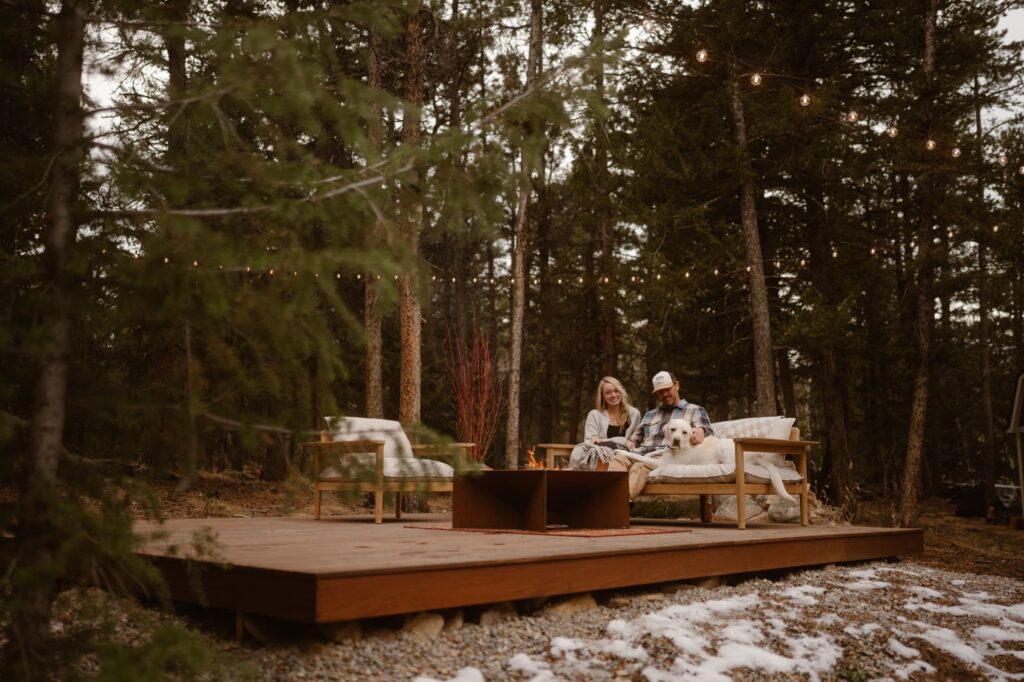 Couple on outdoor furniture in the forest with their dog