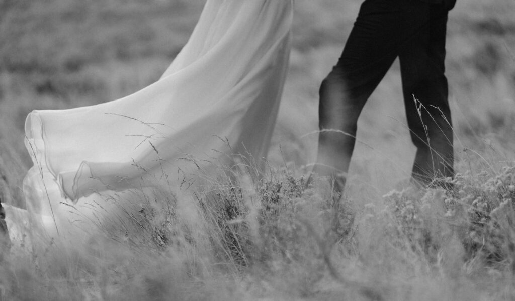 Black and white image of wedding dress and grass blowing in the wind