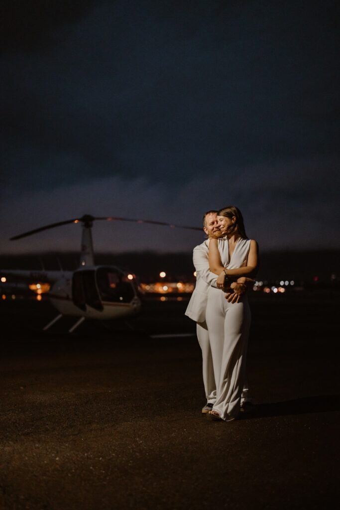 Couple in front of a helicopter at sunrise on their elopement day