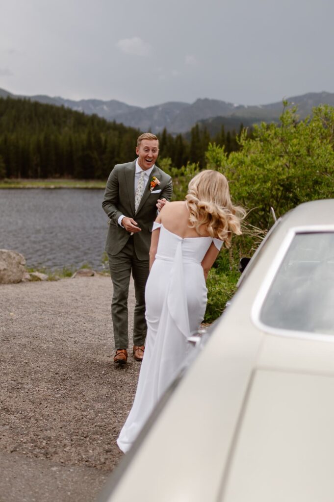Groom surprised by his wife standing in front of a vintage car