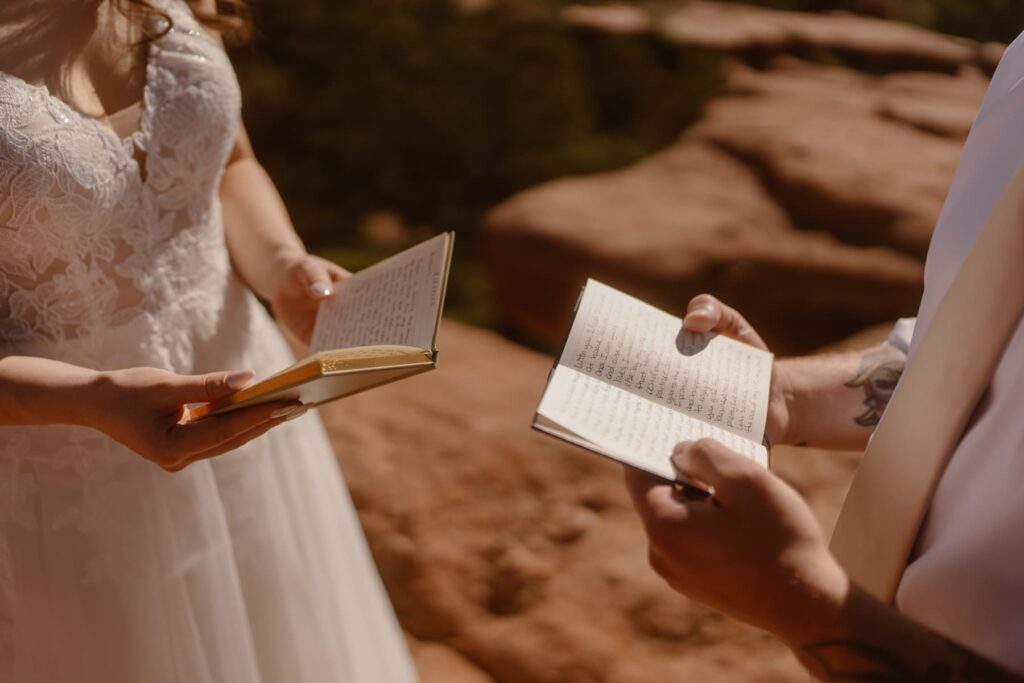 Couple holding their vow books on the red rocks