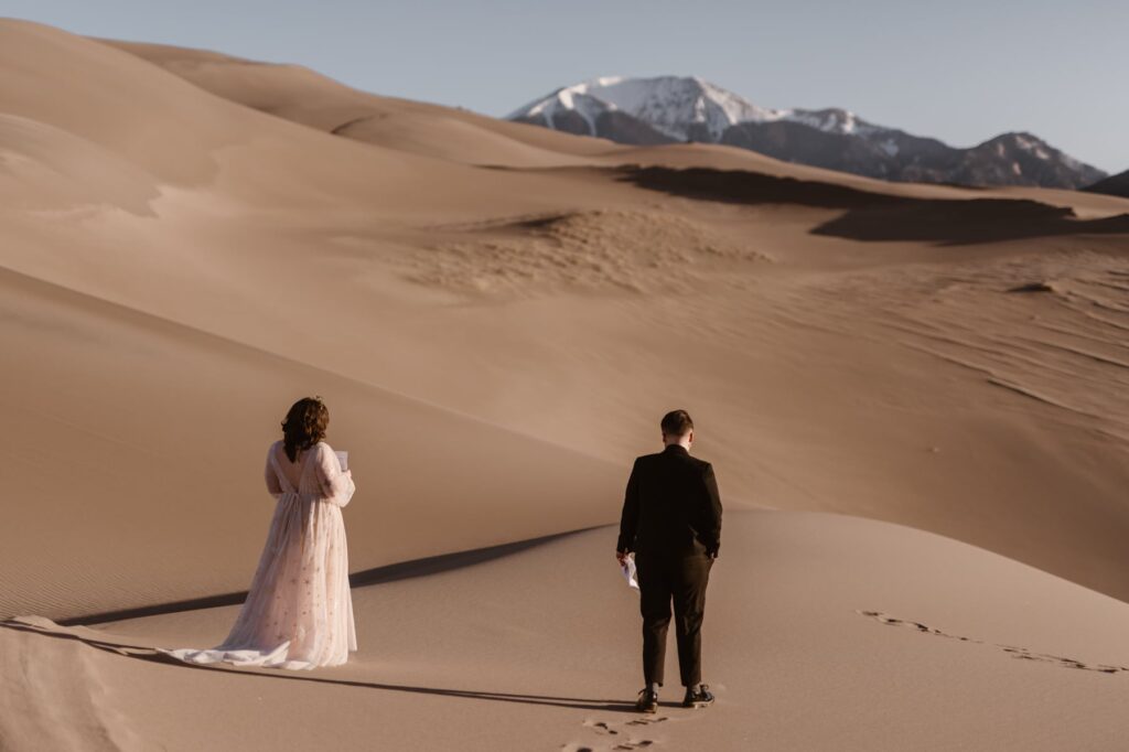 Couple walking out on the sand dunes for their wedding ceremony