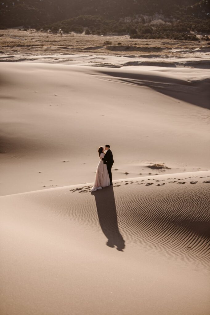 Wedding couple standing on top of sand dunes in Colorado on their elopement day