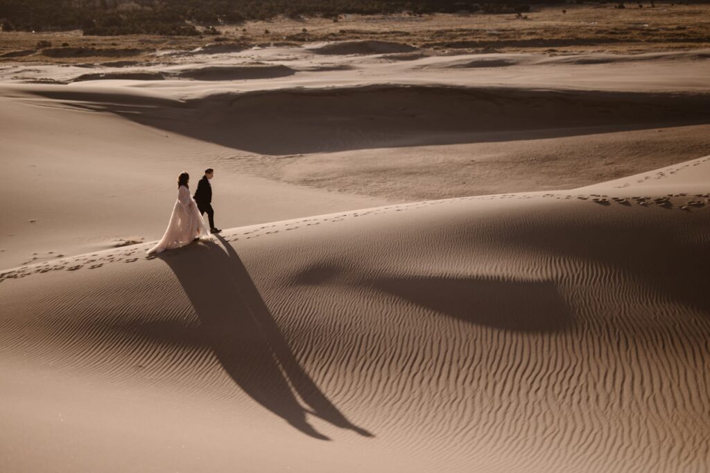 Couple walking the ridge of the sand dunes at sunrise