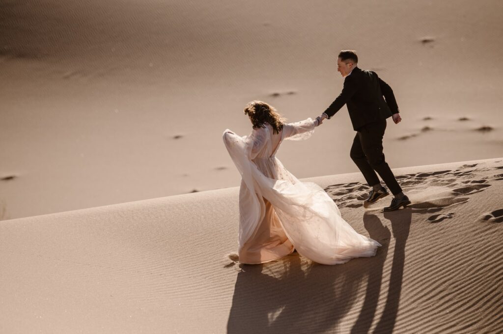 Running down sand dunes in wedding attire