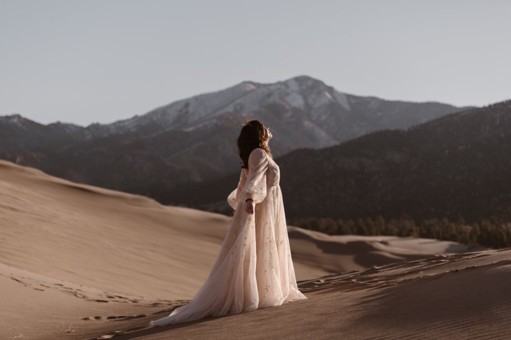 Bride in a colored wedding dress soaking in the sun on the sand dunes