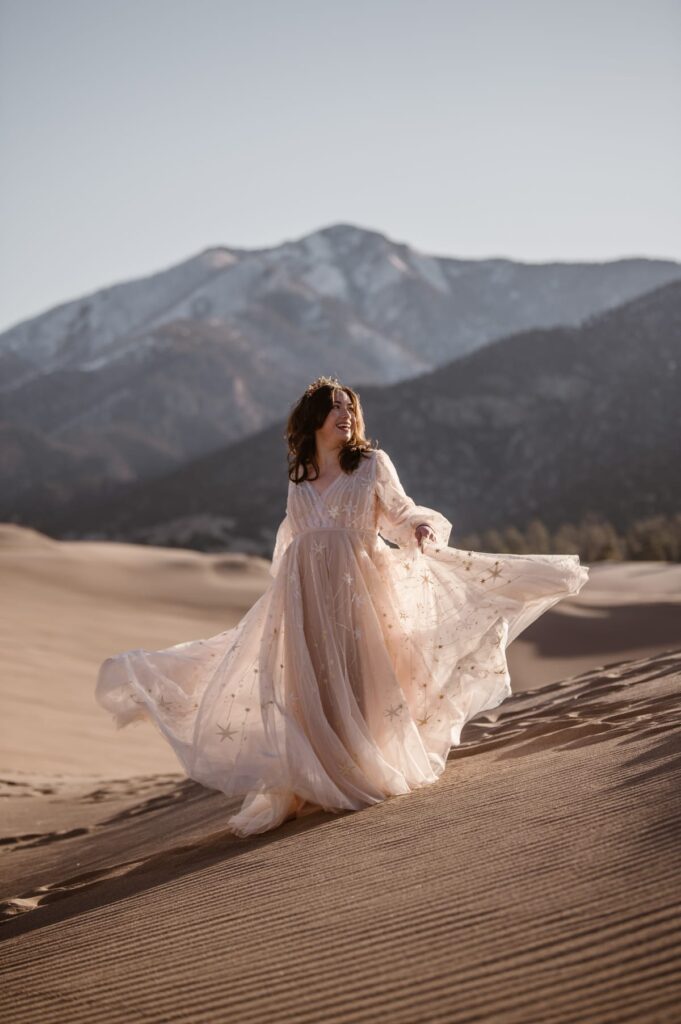 Amazing bridal portrait on top of the sand dunes with mountains in the distance in Colorado