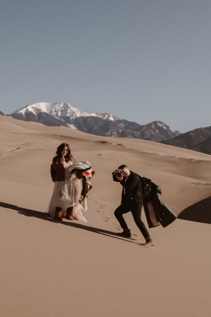 Couple walking down from the sand dunes and taking photos of each other