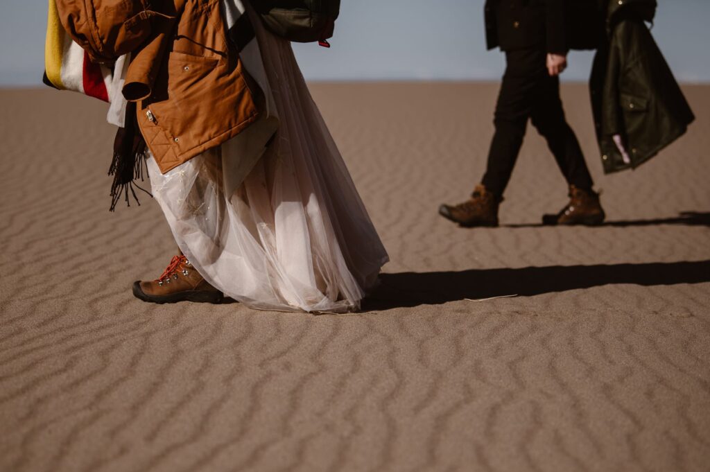 Boots with wedding dress walking through sand 
