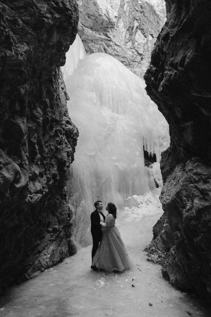 Couple standing in front of a frozen waterfall in Colorado on their elopement day