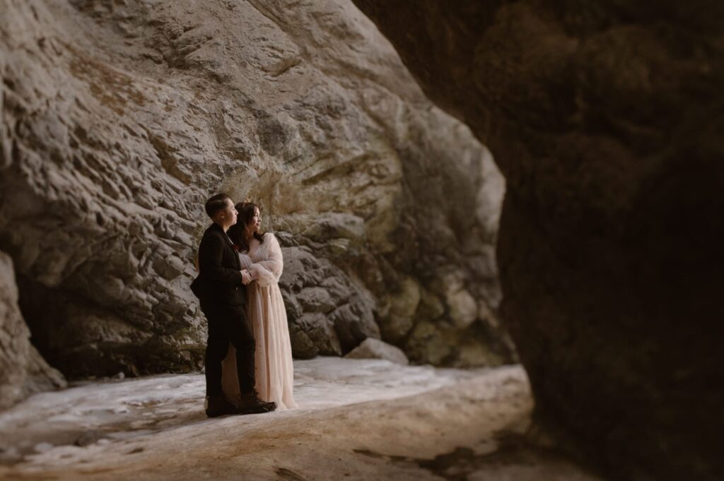 Couple hiking through a frozen waterfall on their elopement day near Great Sand Dunes