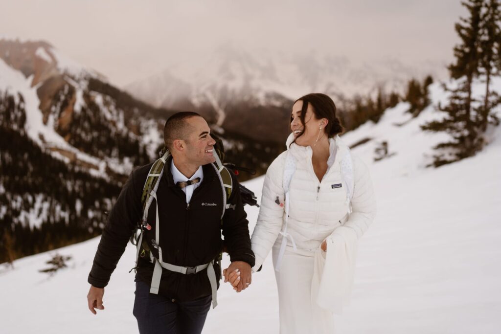 Couple laughing and hiking through the snowy mountains of Ouray, Colorado