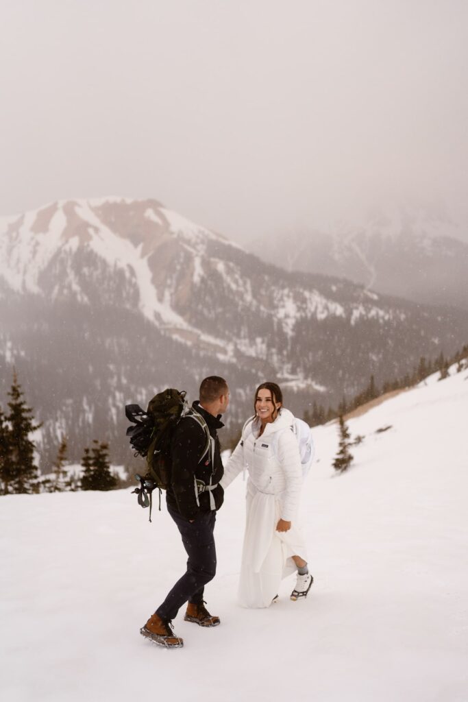 Bride and groom hiking up a snowy mountain in Ouray, Colorado