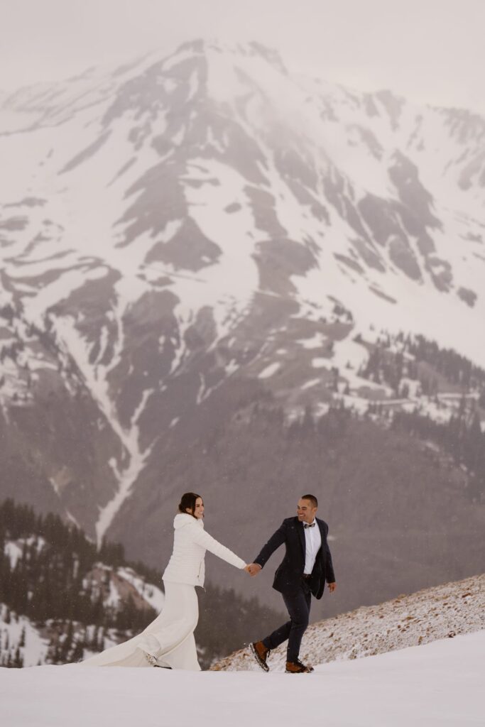 Epic portrait of bride and groom hiking on a snowy mountain