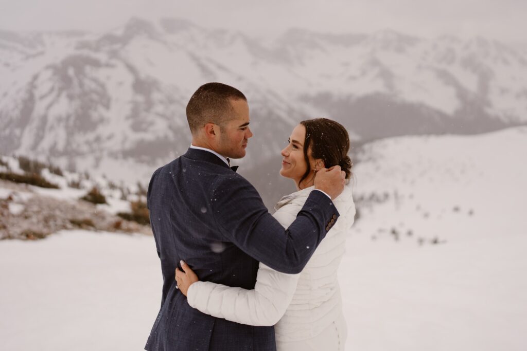 Bride and groom in the mountains as it snows