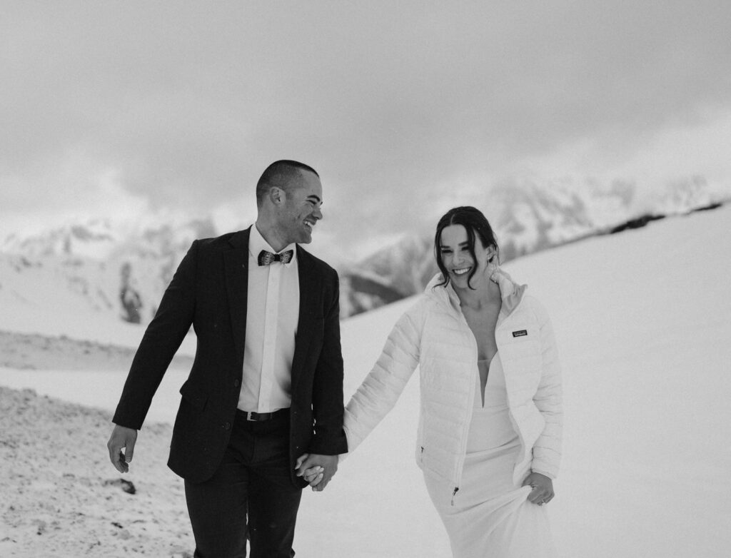 Romantic black and white image of couple hiking on their snowy Spring wedding day