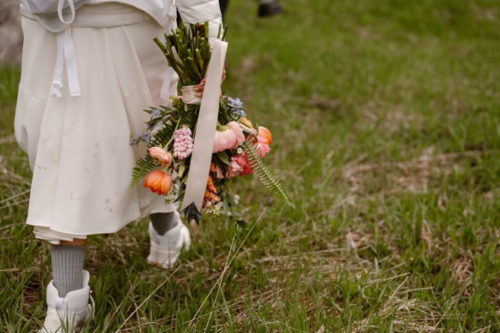 Bride walking off into a meadow with her bouquet and boots