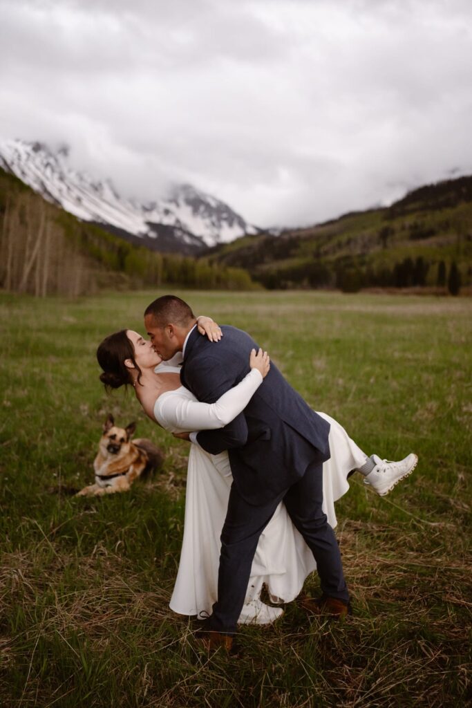 Couple shares a dip in the meadow while their dog watches