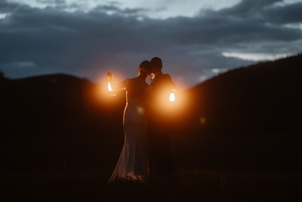 Bride and groom looking out on blue sky with glowing orange lanterns