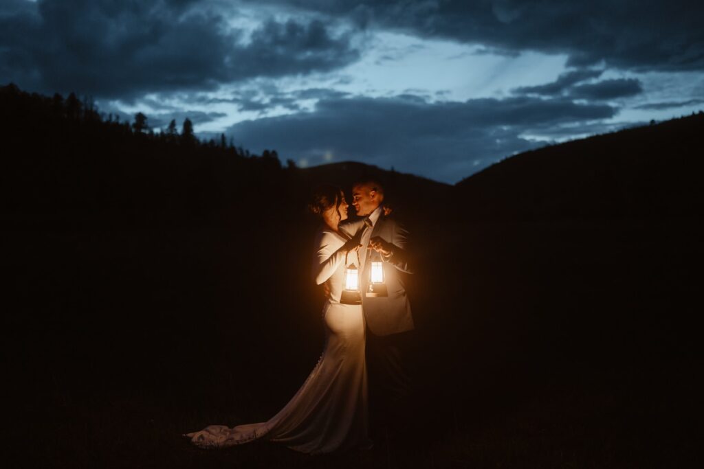 Bride and groom with lanterns after sunset in the mountains