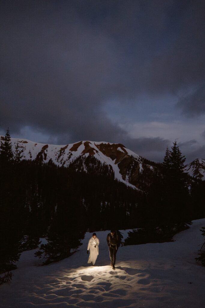 Couple hiking through the snow to the top of a mountain in Ouray, Colorado on their wedding day