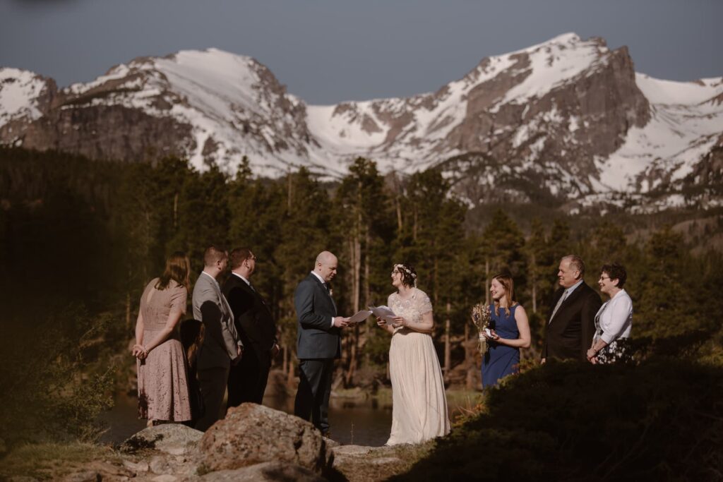 Small wedding ceremony at Sprague Lake with snowcapped mountains