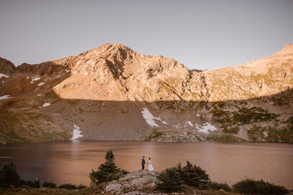 Small wedding couple in front of a large alpine lake in Colorado 