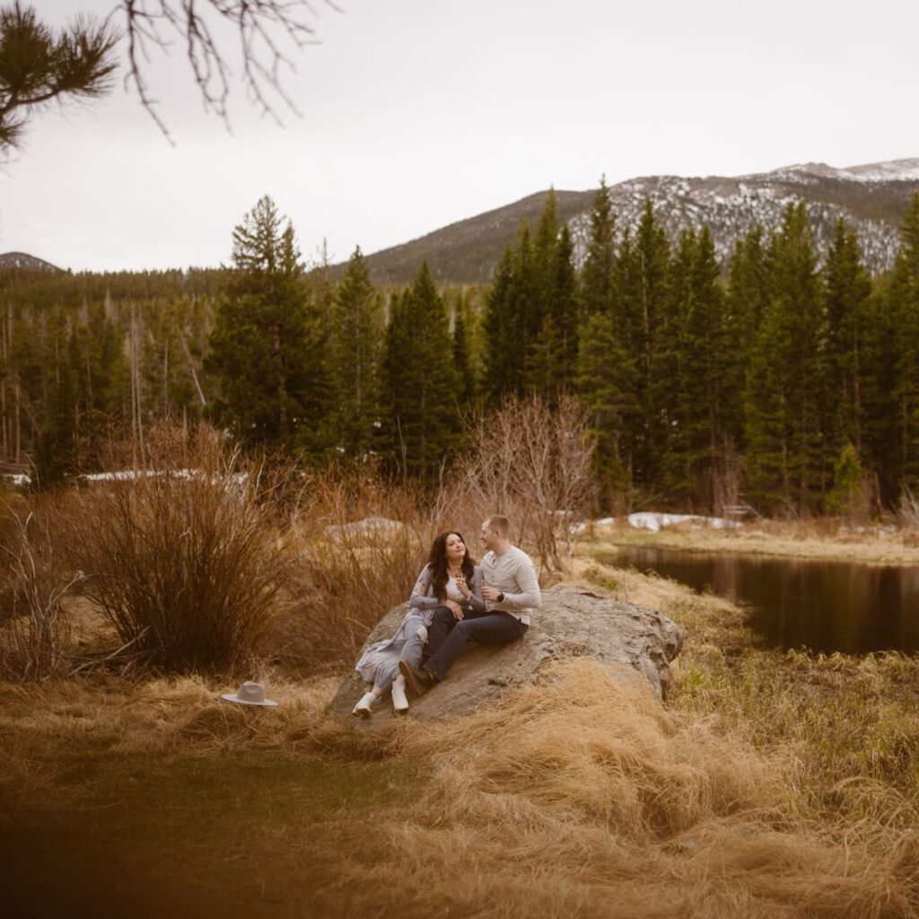 Couple sitting by the lake in the mountains of Colorado during their engagement photos