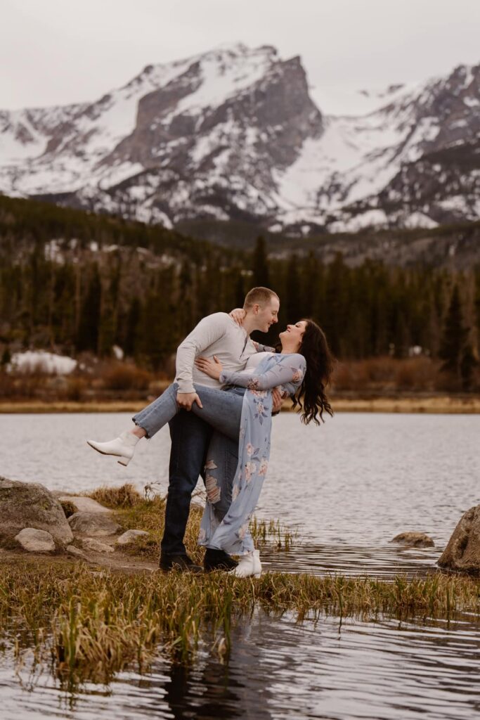 Couple dipping over the lake with mountains in the background during their Colorado engagement photo session