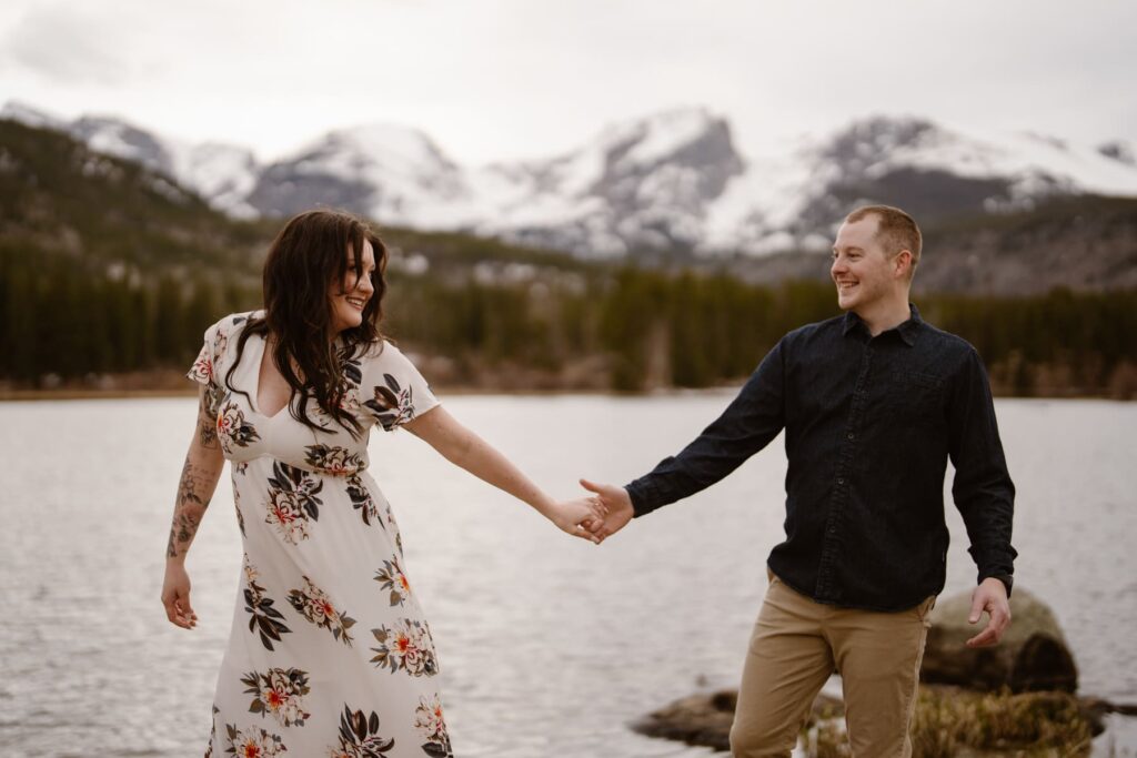 Couple holding hands and walking along Sprague Lake in Estes Park, Colorado