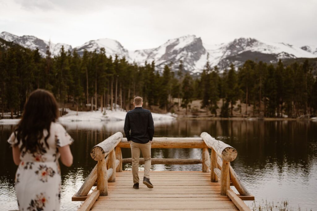Couple walking out onto the dock at Sprague Lake during their engagement photography session