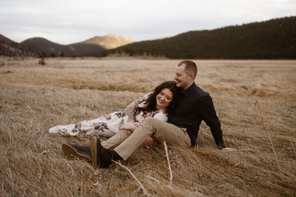 Couple laying in an open meadow in Colorado during engagement photos