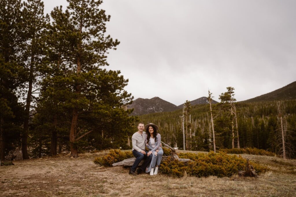 Couple sitting on a log in the mountains during their Colorado engagement photo session