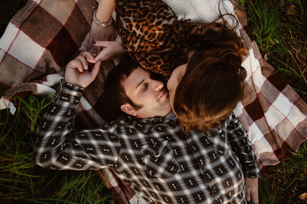 Couple snuggled up on a picnic blanket together