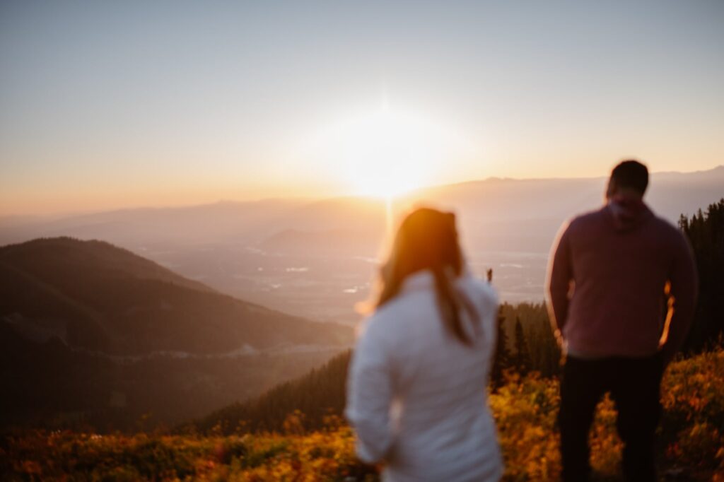 Couple walking off into the sunrise overlooking the mountains
