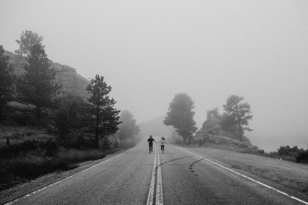 Couple running down a foggy street together in Colorado
